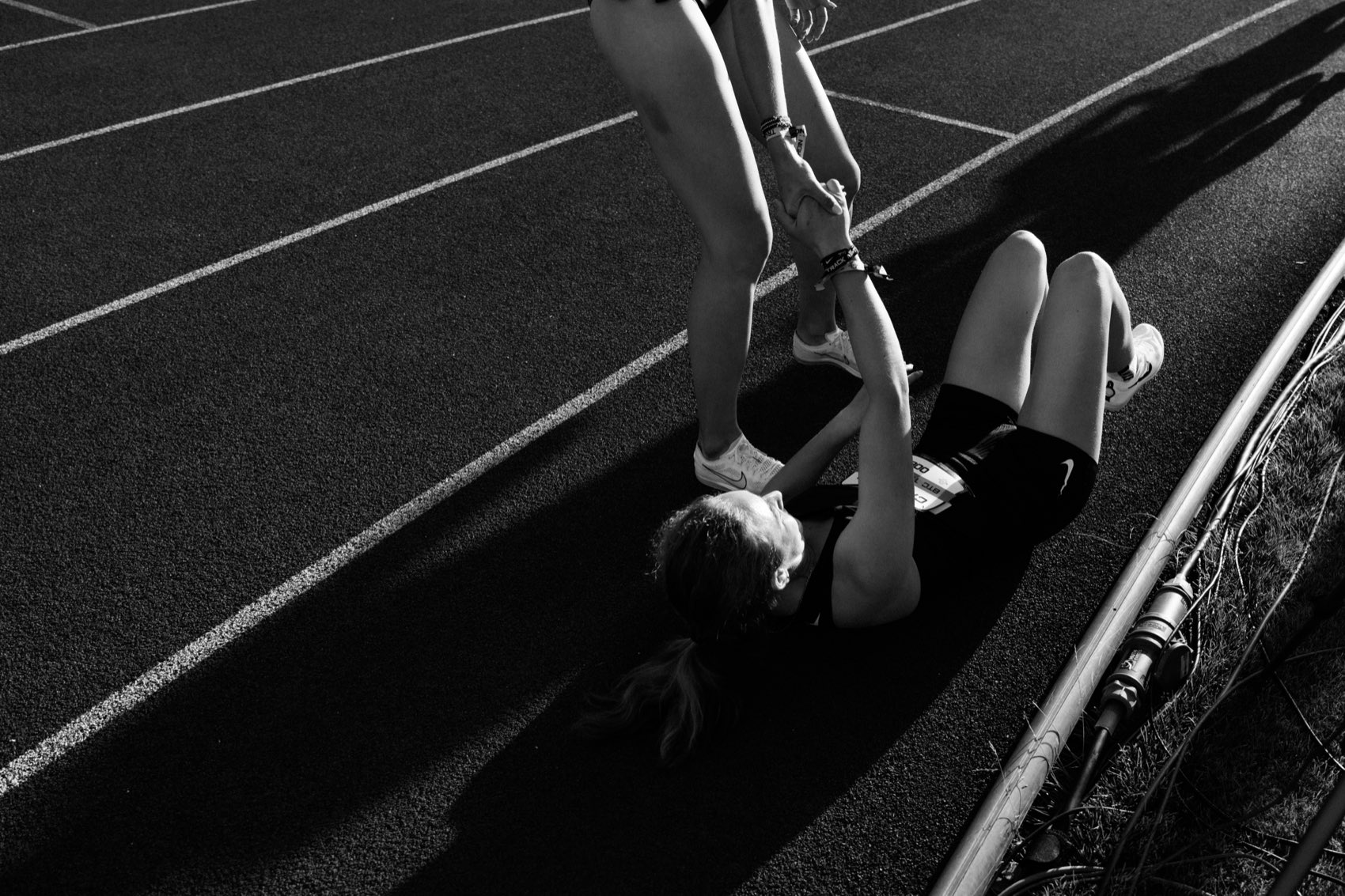 A runner helping another up from the track after a race